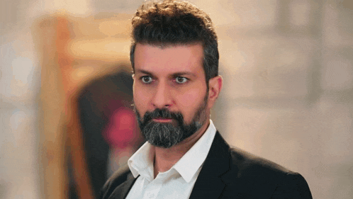 a man with a beard is wearing a suit and a white shirt