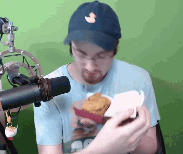 a man wearing a blue hat with a duck on it is holding a box of food