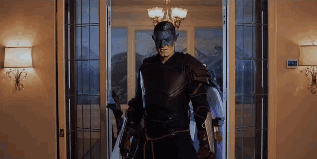 a man in a superhero costume is standing in a doorway with a clock on the wall that reads 10:08