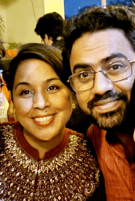 a man and woman are posing for a picture and the woman is wearing glasses