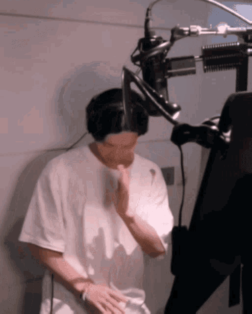 a man in a white shirt is standing in front of a microphone .