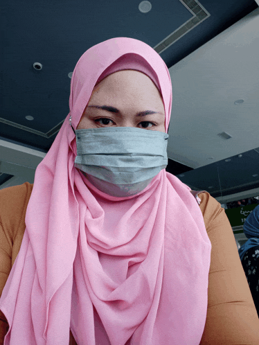 a woman wearing a pink scarf and a mask