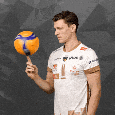 a man in a white shirt with the word plus on it holds a volleyball