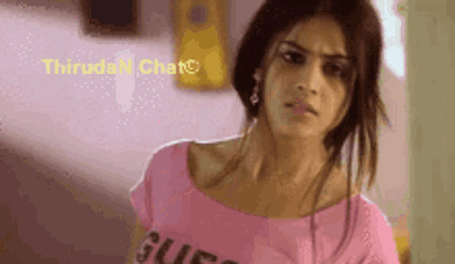 a woman wearing a pink shirt that says guess on it