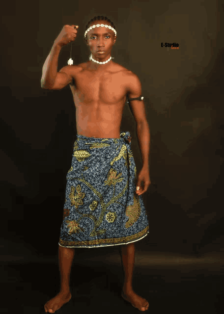 a shirtless man in a blue and gold skirt is holding a pendulum
