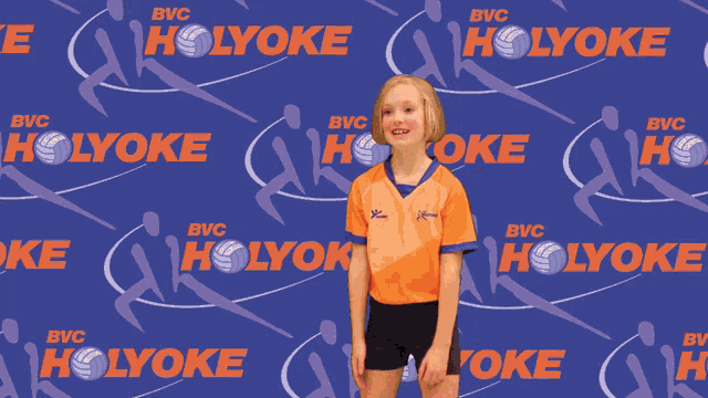 a girl is playing volleyball in front of a holyoke logo