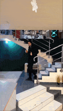 a man walking down a set of stairs holding a cup