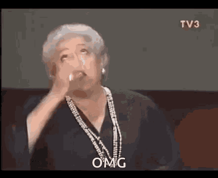 a woman with gray hair and a pearl necklace is making a funny face and says omg .