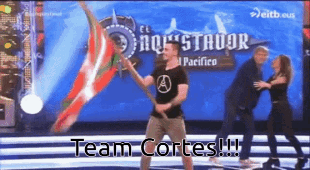 a man is holding a stick in front of a sign that says " team cortes "