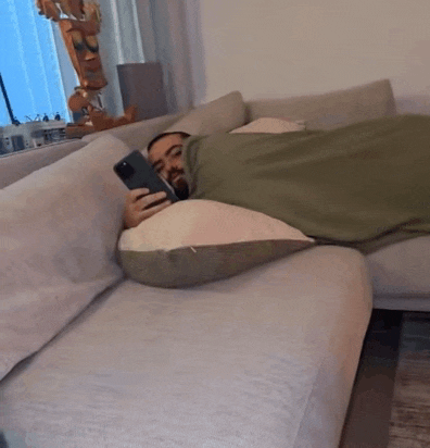 a man laying on a couch holding a phone