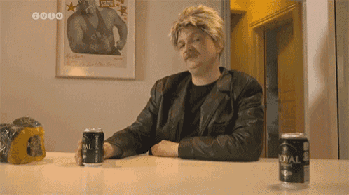 a man sits at a table with two cans of royal