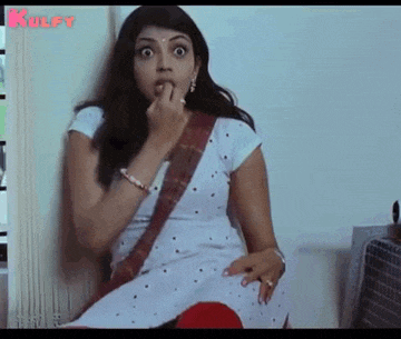 a woman in a white dress is biting her nails while sitting on a couch .