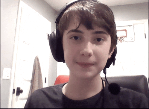 a young man wearing headphones and a microphone looks at the camera
