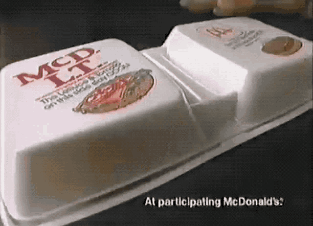 two styrofoam containers of mcdonald 's food are sitting on top of a table .