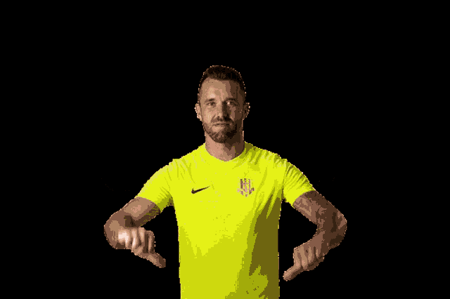 a man wearing a neon yellow nike shirt is pointing at something