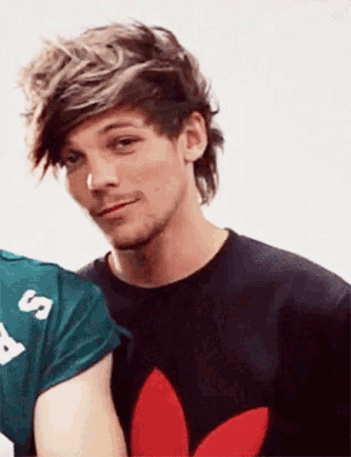 a close up of a man wearing a black shirt with a red adidas logo