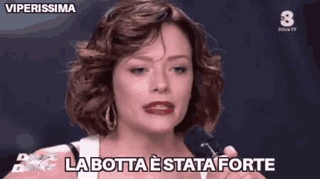 a woman is crying while holding a microphone and says `` la botta e stata forte '' .