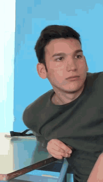 a young man in a grey shirt is sitting at a table