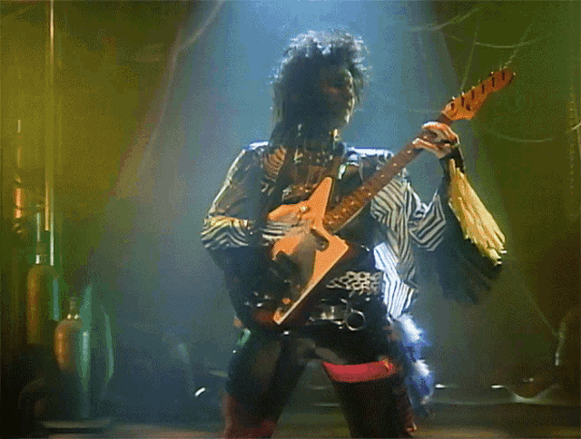 a man with long hair is playing a guitar on stage