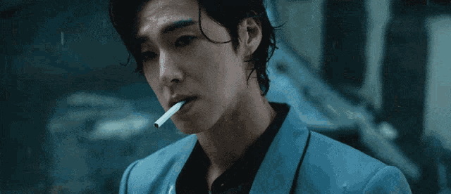 a man in a blue jacket is smoking a cigarette