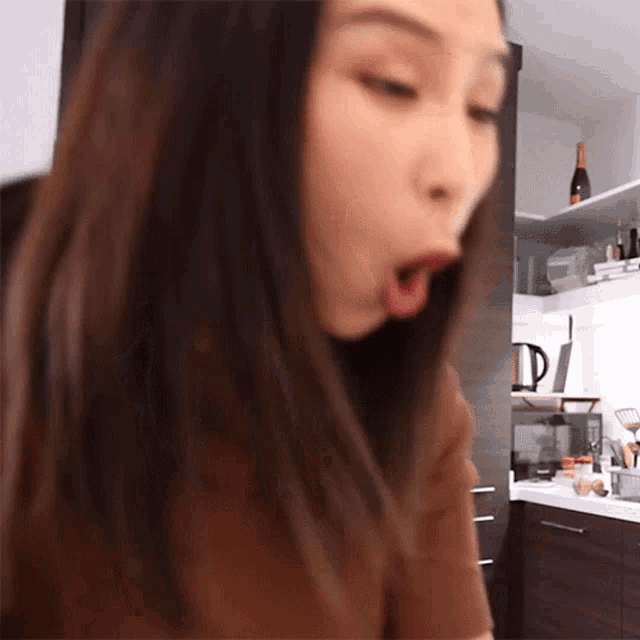 a woman is sitting in a kitchen with her mouth wide open