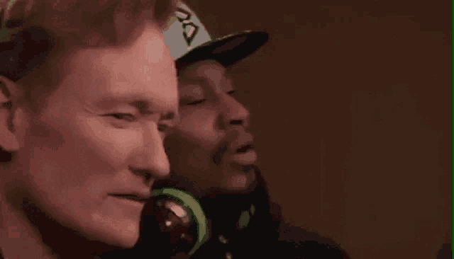 snoop dogg and conan o'brien are sitting next to each other wearing headphones and hats .