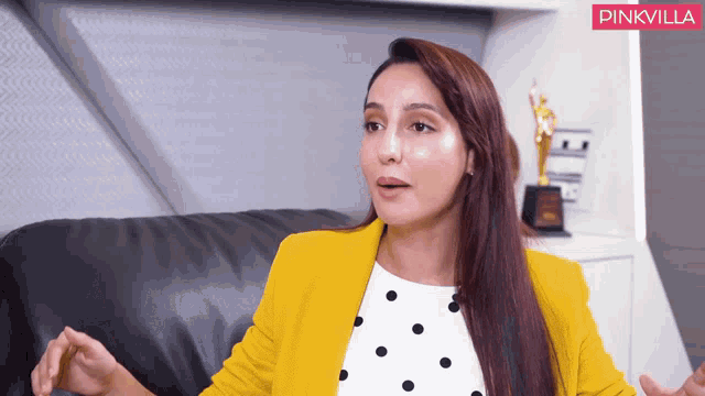 a woman in a yellow jacket is sitting on a black leather couch