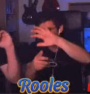 a man covering his face with his hands in front of a sign that says ' rooles ' on it