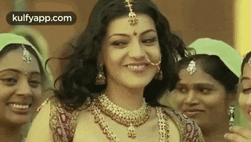 a woman in a wedding dress is smiling while standing in front of a group of women .