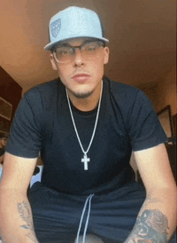 a man wearing glasses and a hat has a cross on his necklace