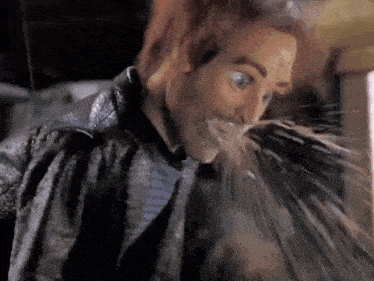 a man in a leather jacket is drinking water from a bottle .
