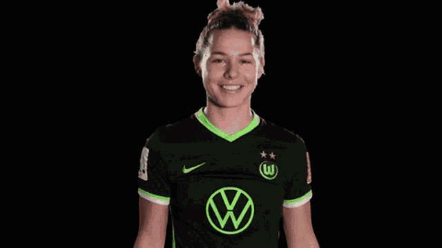 a woman wearing a black shirt with a green vw logo on it