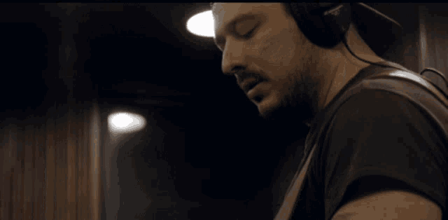 a man wearing headphones stands in front of the words the fuck