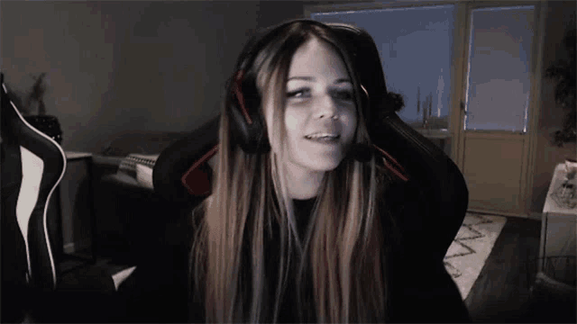 a woman wearing headphones is sitting in a chair and smiling