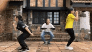 a group of people are squatting on the ground in front of a building .