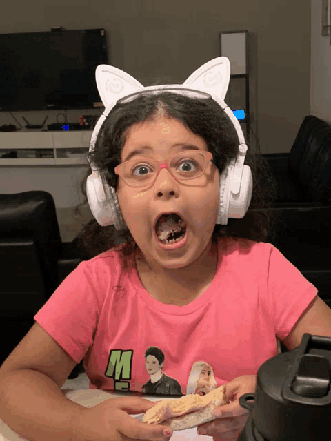 a little girl wearing headphones and a pink shirt that says m on it