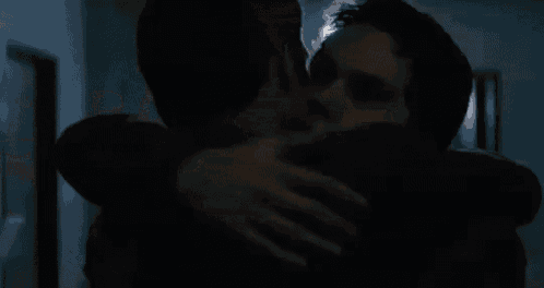 a couple of men are hugging each other in the dark .