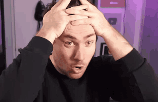 a man in a black shirt is holding his head in his hands