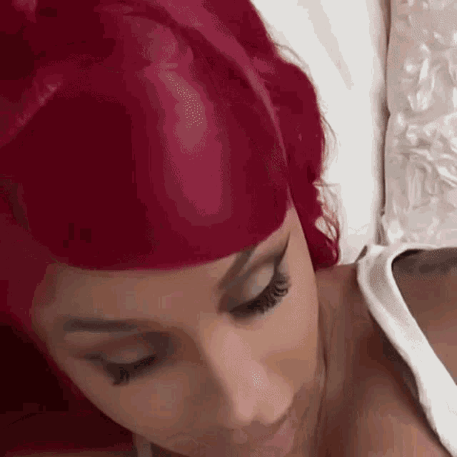 a woman with red hair is laying on a bed with her eyes closed and her mouth open .