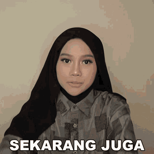 a woman wearing a hijab and a shirt with the words sekarang juga written below her