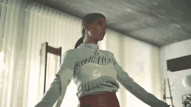 a woman is standing in a room with her arms outstretched .