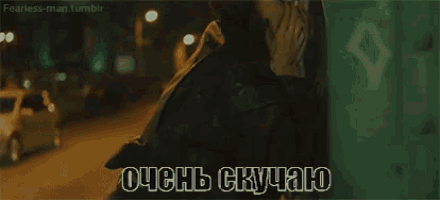 a man is walking down a street at night and talking on a cell phone in russian .