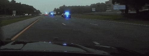 a police car is driving down a highway with a blue light on the back of it