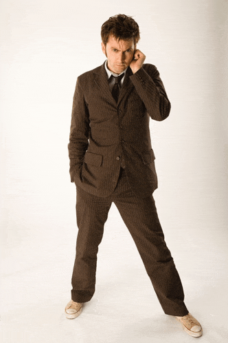 a man in a suit and tie standing with his hands in his pockets