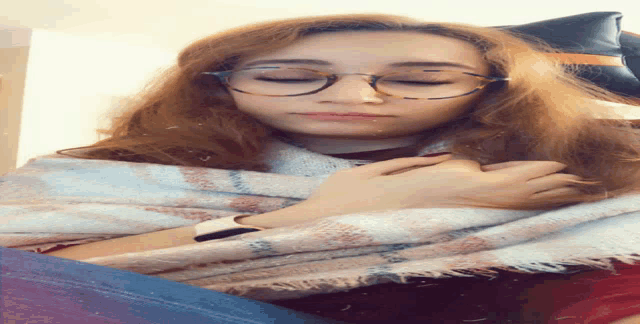 a woman wearing glasses and a scarf is sleeping