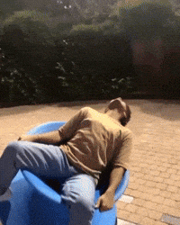 a man is laying on a blue chair on a brick sidewalk