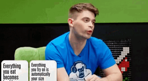 a man wearing a blue shirt that says everything you eat automatically becomes your size is sitting at a table .