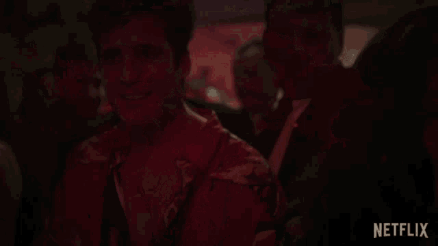 a man in a red shirt is dancing in a dark room with netflix written on the bottom