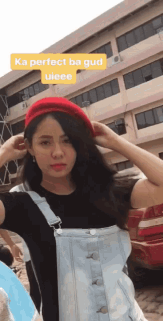 a woman wearing overalls and a red hat with the words ka perfect ba gud uieee above her