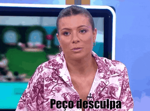 a woman in a floral shirt is sitting in front of a television and says peco desculpa